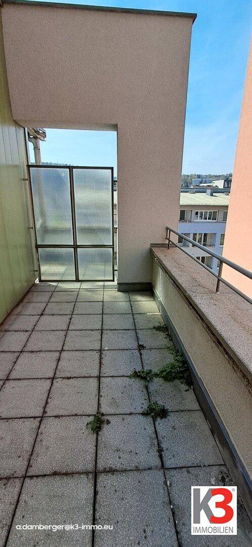 Gefliester Balkon mit Glasabtrennung, der einen Außenbereich zum Entspannen bietet.