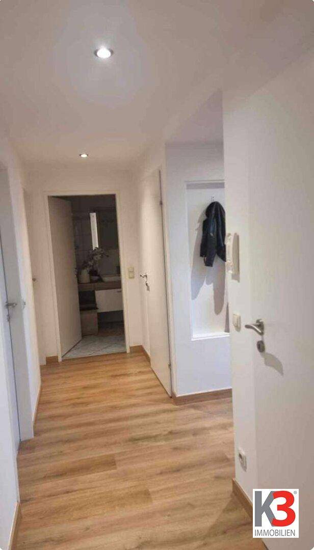 Geräumiger Flur mit hellem Holzboden, mehreren Türen und einer praktischen Garderobennische.