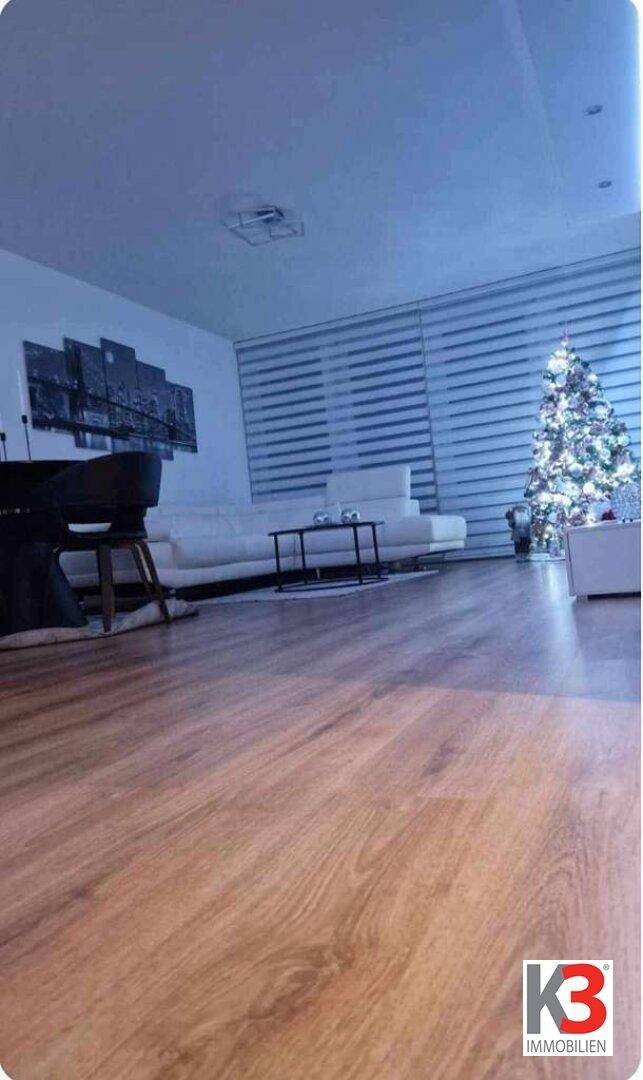 Wohnzimmer mit hellem Holzboden und festlicher Weihnachtsdekoration, die eine gemütliche Atmosphäre schafft.