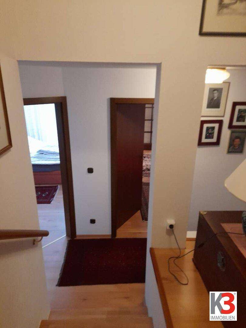 Heller Flur mit Holztreppe und Zugang zu weiteren Zimmern, traditionell gestaltet.