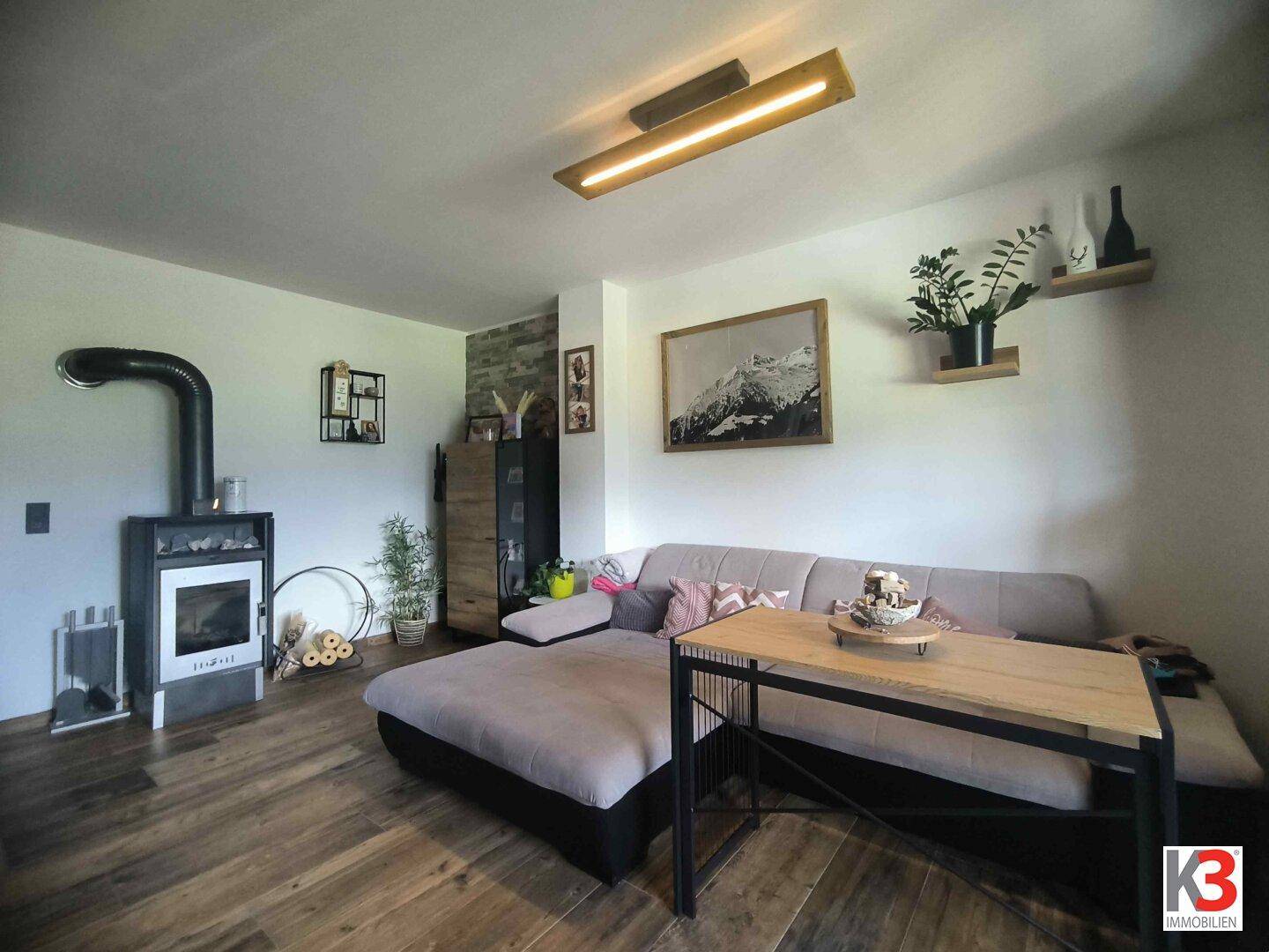 Gemütliches Wohnzimmer mit Holzboden, modernem Kaminofen und bequemer Sitzecke.