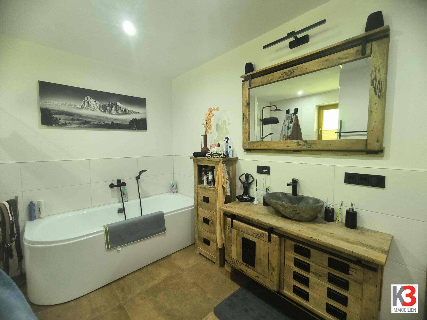Modernes Badezimmer mit Badewanne, stilvollem Holzwaschtisch und großem Spiegel.