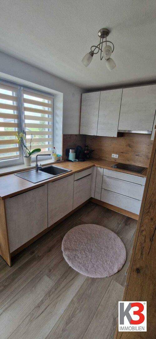 Helle Küche mit Holzoptik-Arbeitsplatten, weißen Schränken und Fenster.
