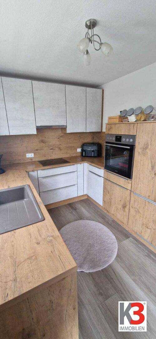 Moderne Küche mit integriertem Backofen, Kochfeld und viel Stauraum.