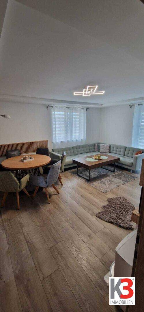 Geräumiger Wohn-Essbereich mit Holzboden, bequemer Sitzecke und modernem Esstisch.
