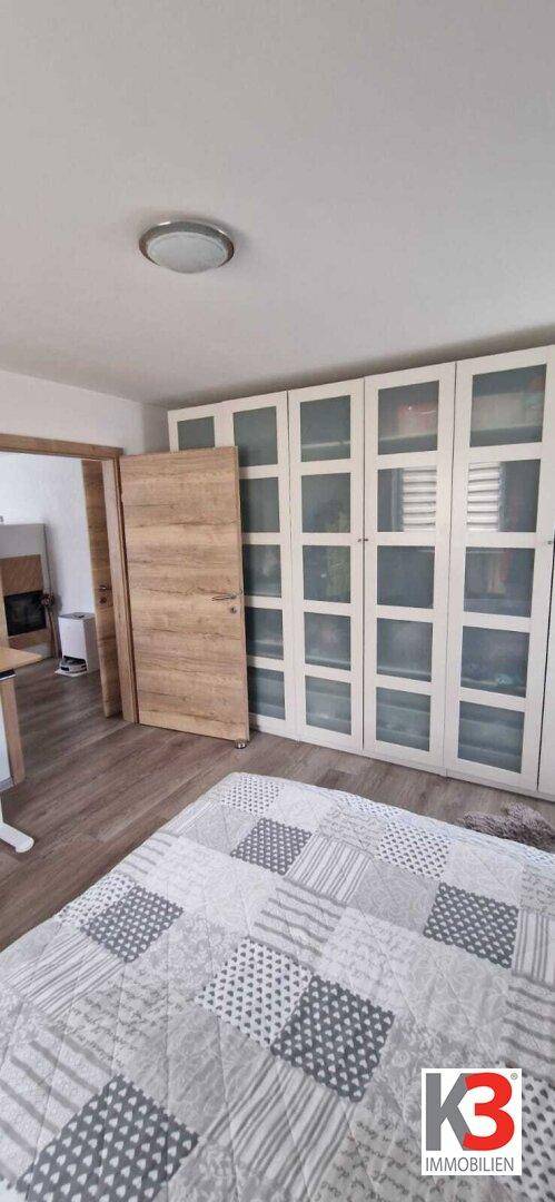 Schlafzimmer mit großem Kleiderschrank und Holzboden, bietet viel Stauraum.
