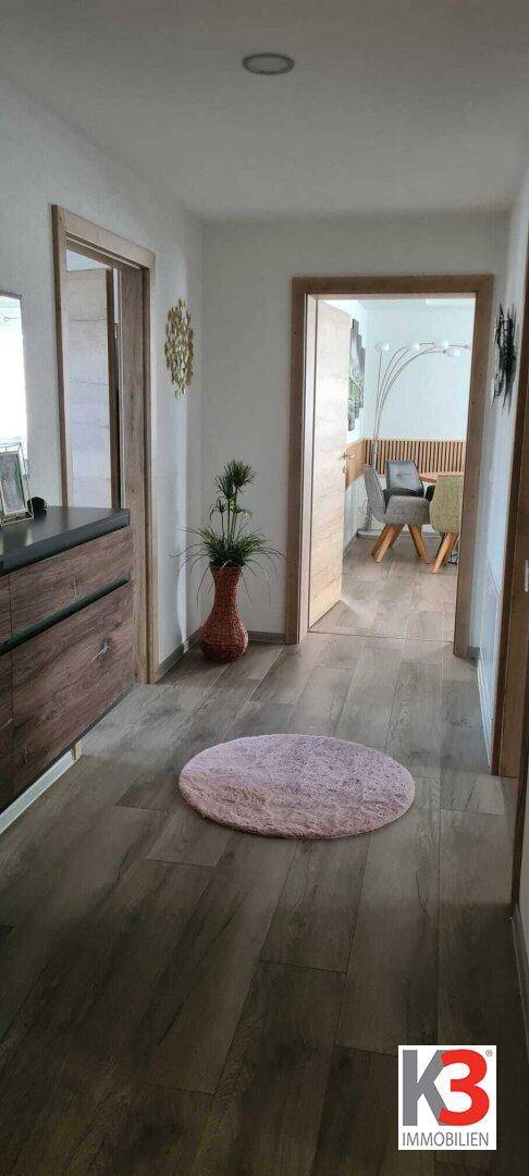 Heller Flur mit Holzboden und Zugang zu weiteren Räumen, modern eingerichtet.