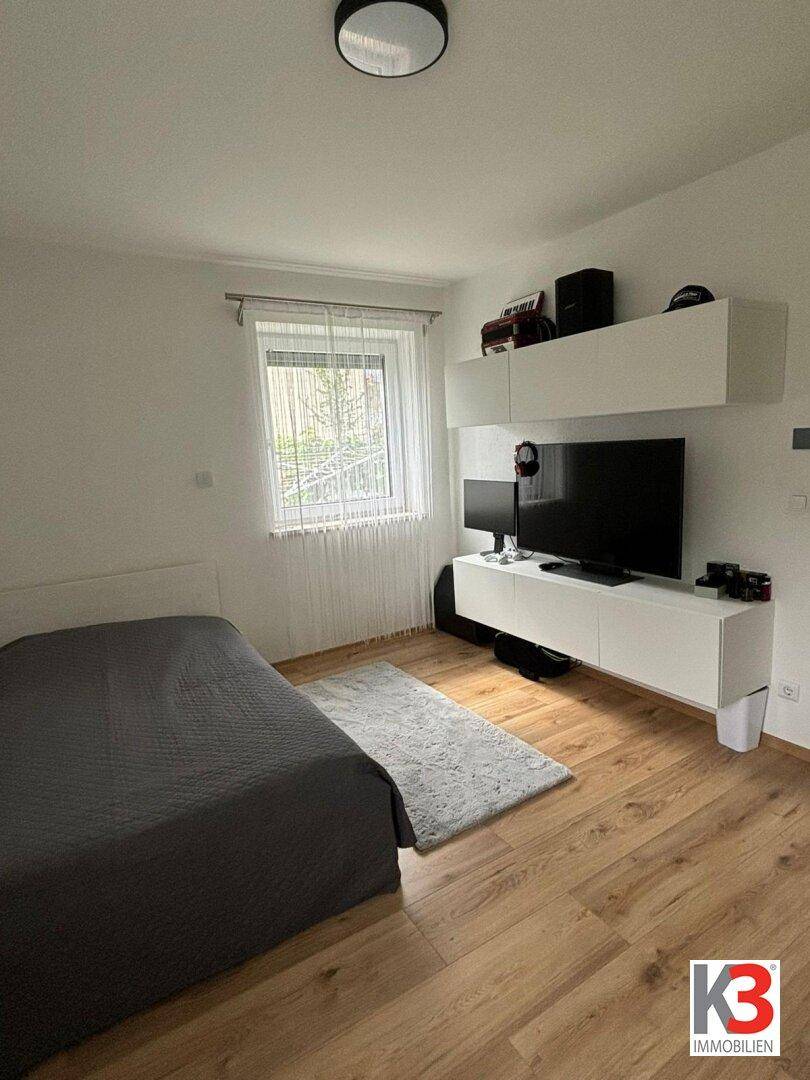 Schlafzimmer mit Bett, TV-Möbeln und Holzboden, bietet eine moderne Einrichtung.
