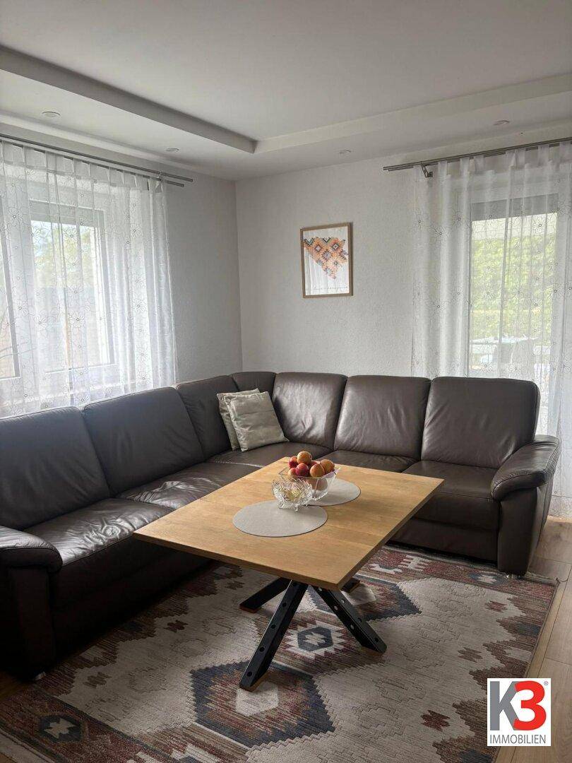 Gemütliches Wohnzimmer mit großem Ledersofa, Couchtisch und Teppich.