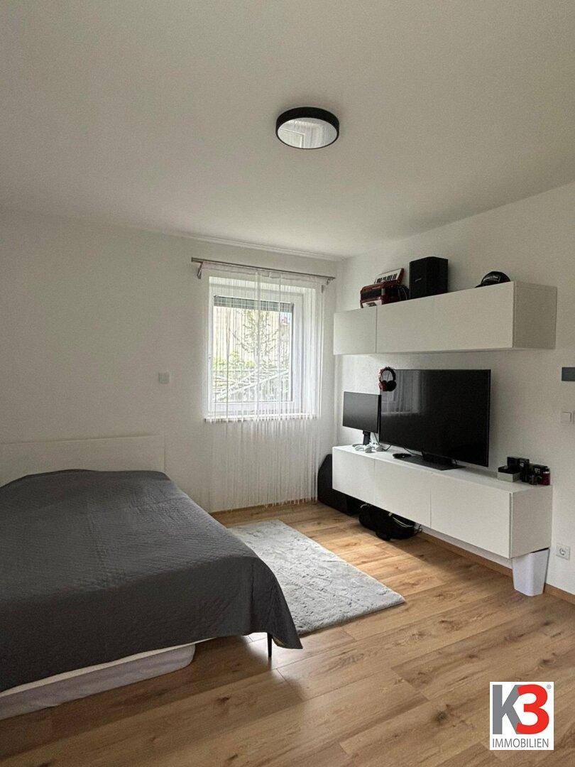 Schlafzimmer mit Bett, TV-Möbeln und Holzboden, bietet eine moderne Einrichtung.