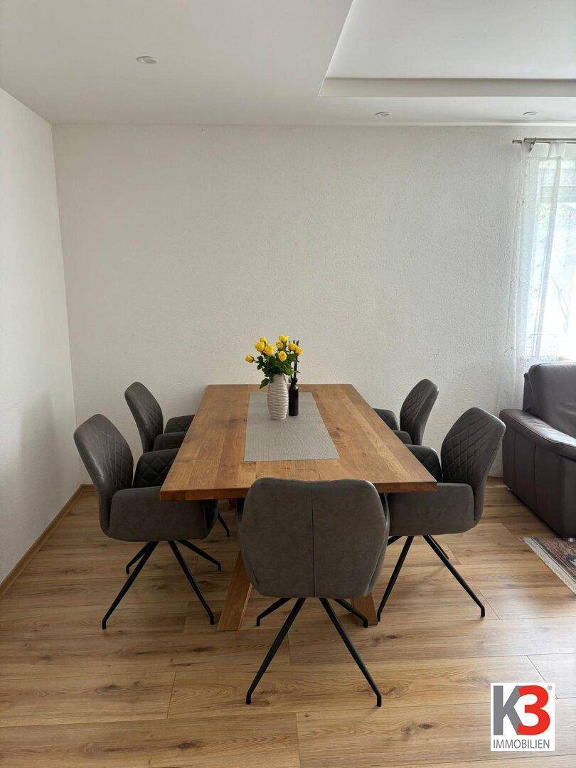 Geräumiger Essbereich mit großem Holztisch und modernen Stühlen, ideal für Familien.