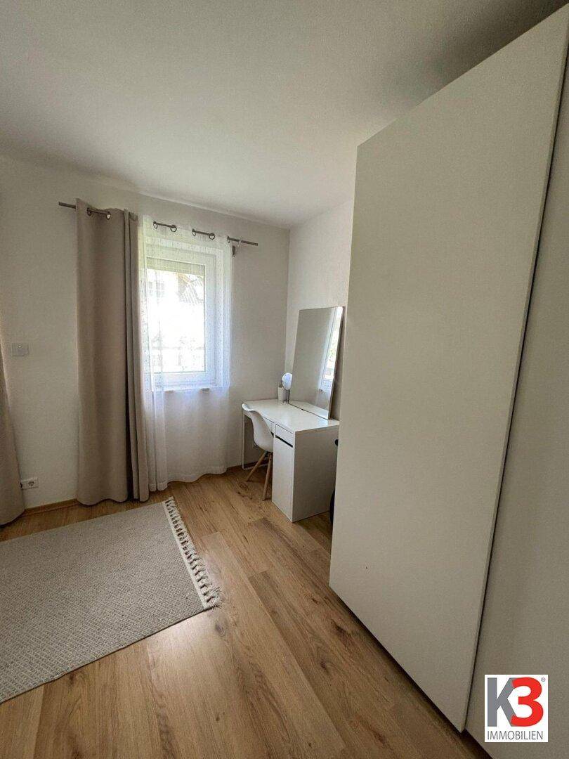 Helles Schlafzimmer mit Schreibtisch, Kleiderschrank und Holzboden, ideal für Gäste.
