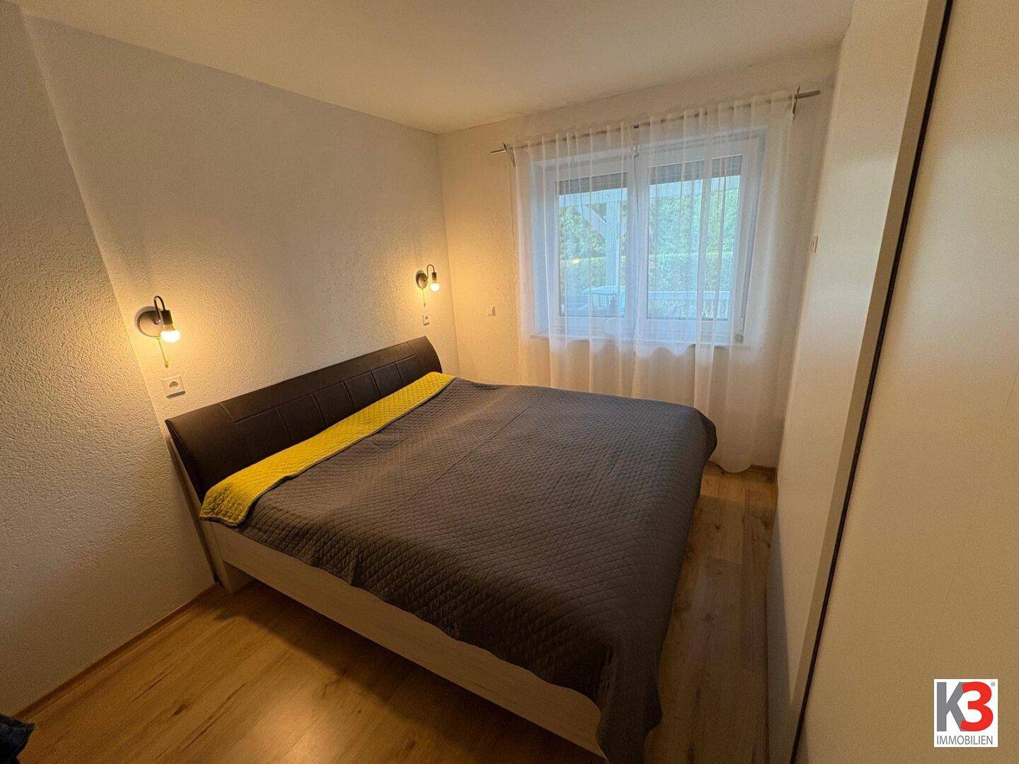 Gemütliches Schlafzimmer mit Doppelbett, Wandlampen und Holzboden, bietet Komfort.