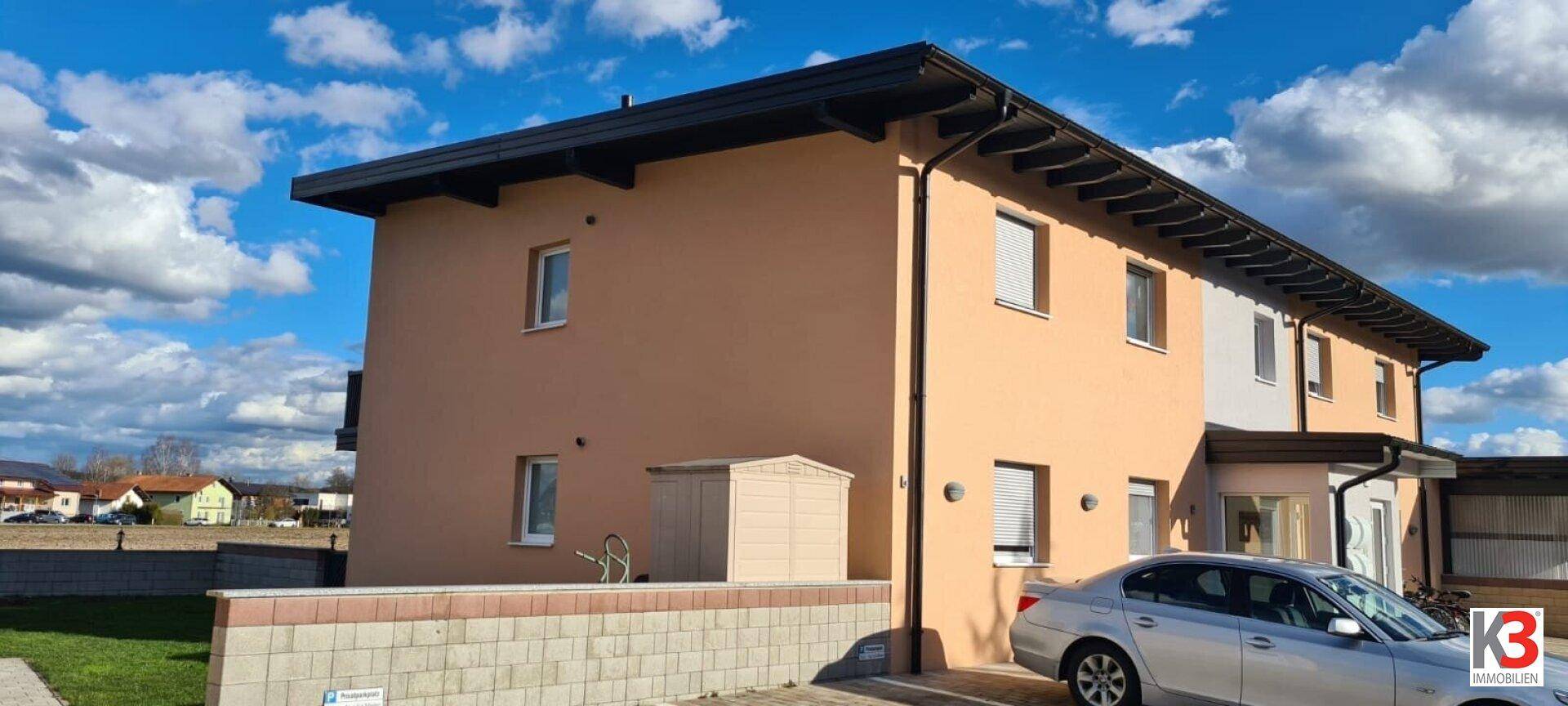 Seitenansicht des modernen Hauses mit gepflegter Fassade und kleinem Geräteschuppen.