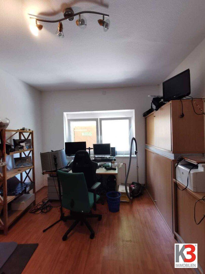 Das Arbeitszimmer im Dachgeschoss mit Schreibtisch, Computern und Holzregalen.