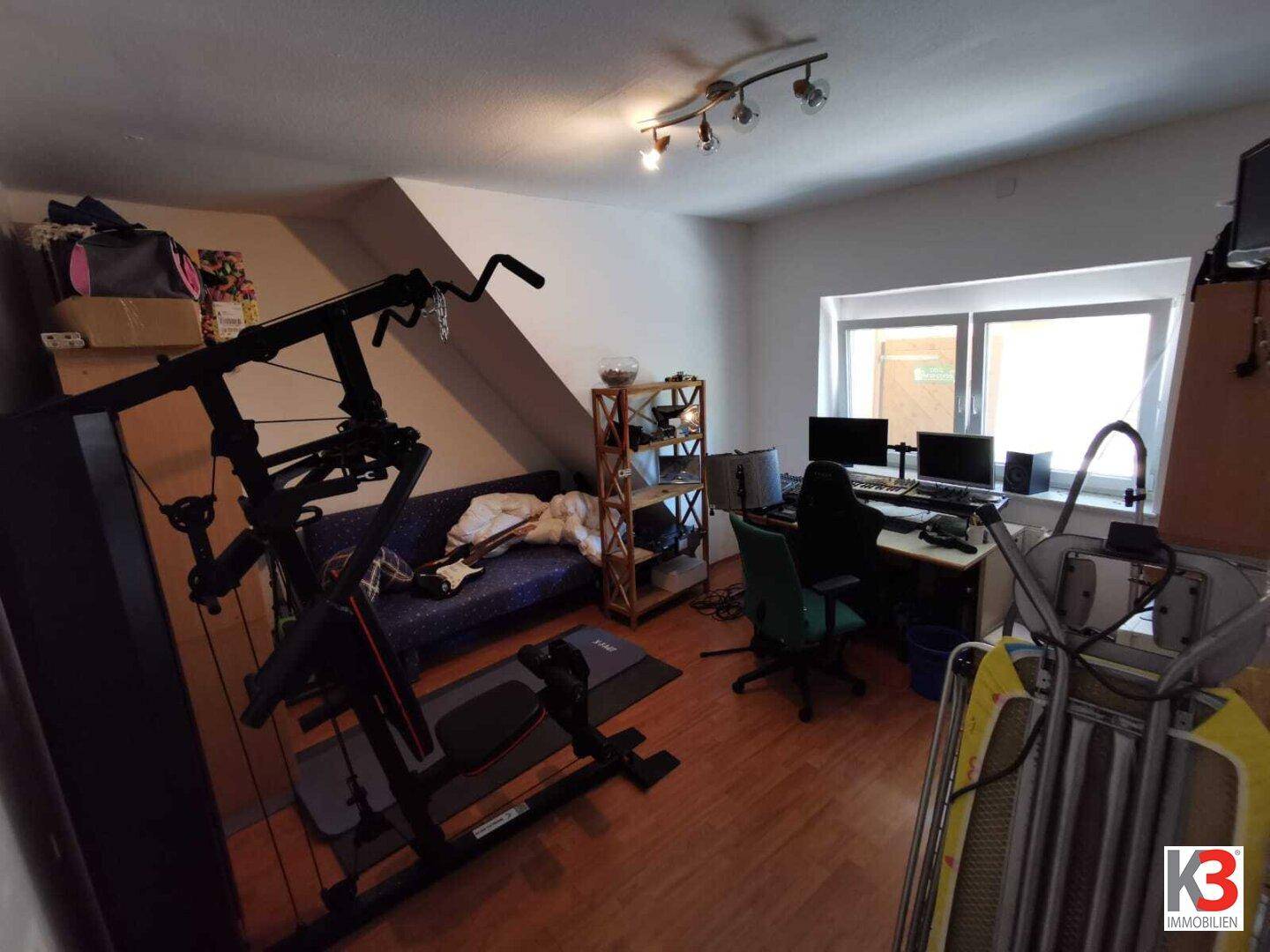 Das Arbeitszimmer im Dachgeschoss mit Schreibtisch, Computer und Fitnessgeräten.