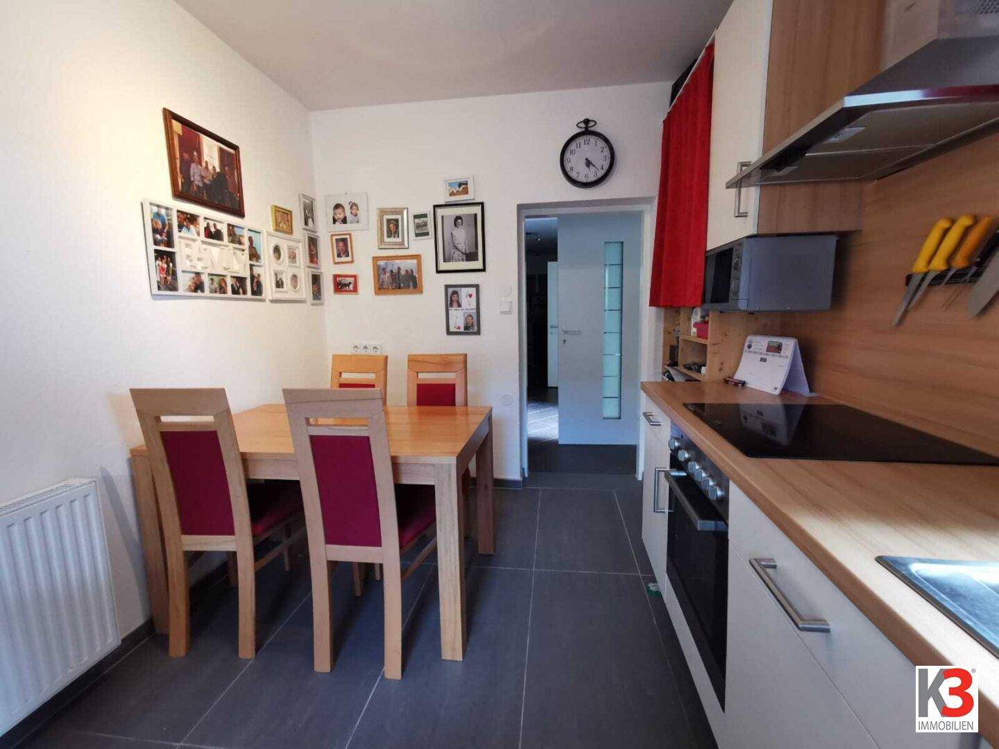 Die Küche mit Essbereich, Holztisch und einer Wand voller Familienfotos.