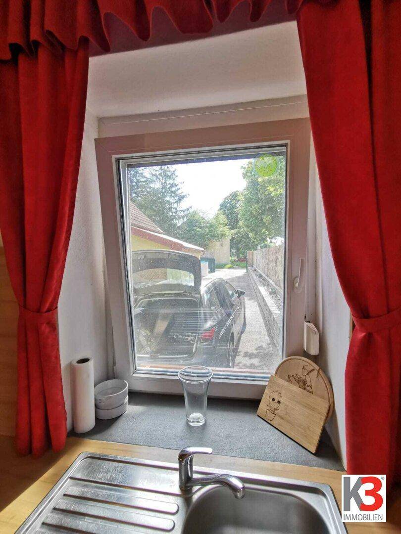Ein Küchenfenster mit Blick auf die Einfahrt und das geparkte Auto.