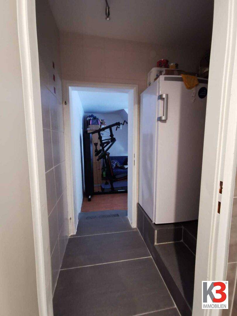 Der Flur mit Gefrierschrank und Blick in einen weiteren Raum.