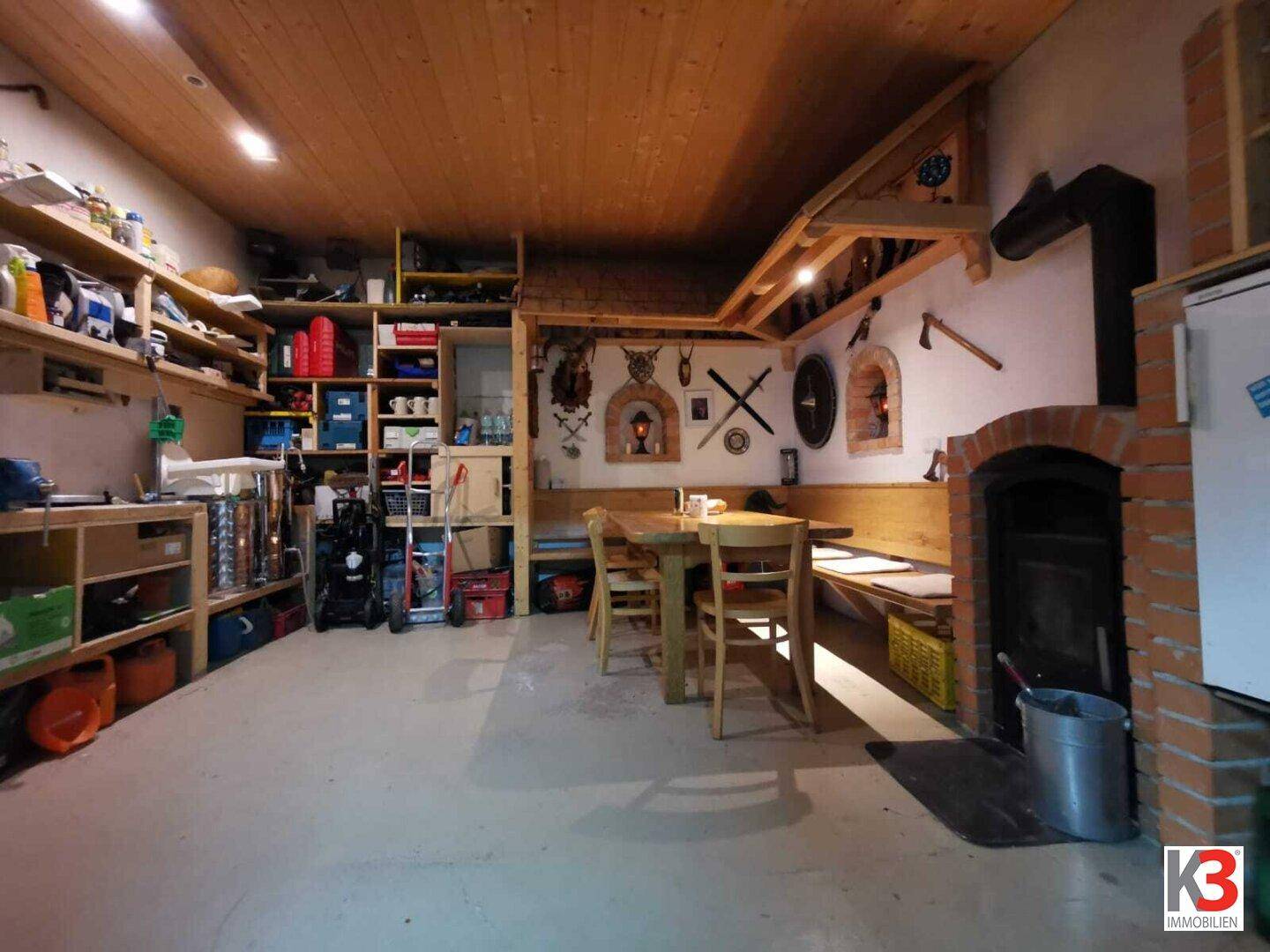Das rustikale Esszimmer mit Kamin, Holztisch, Holzbalkendecke und praktischen Regalen.