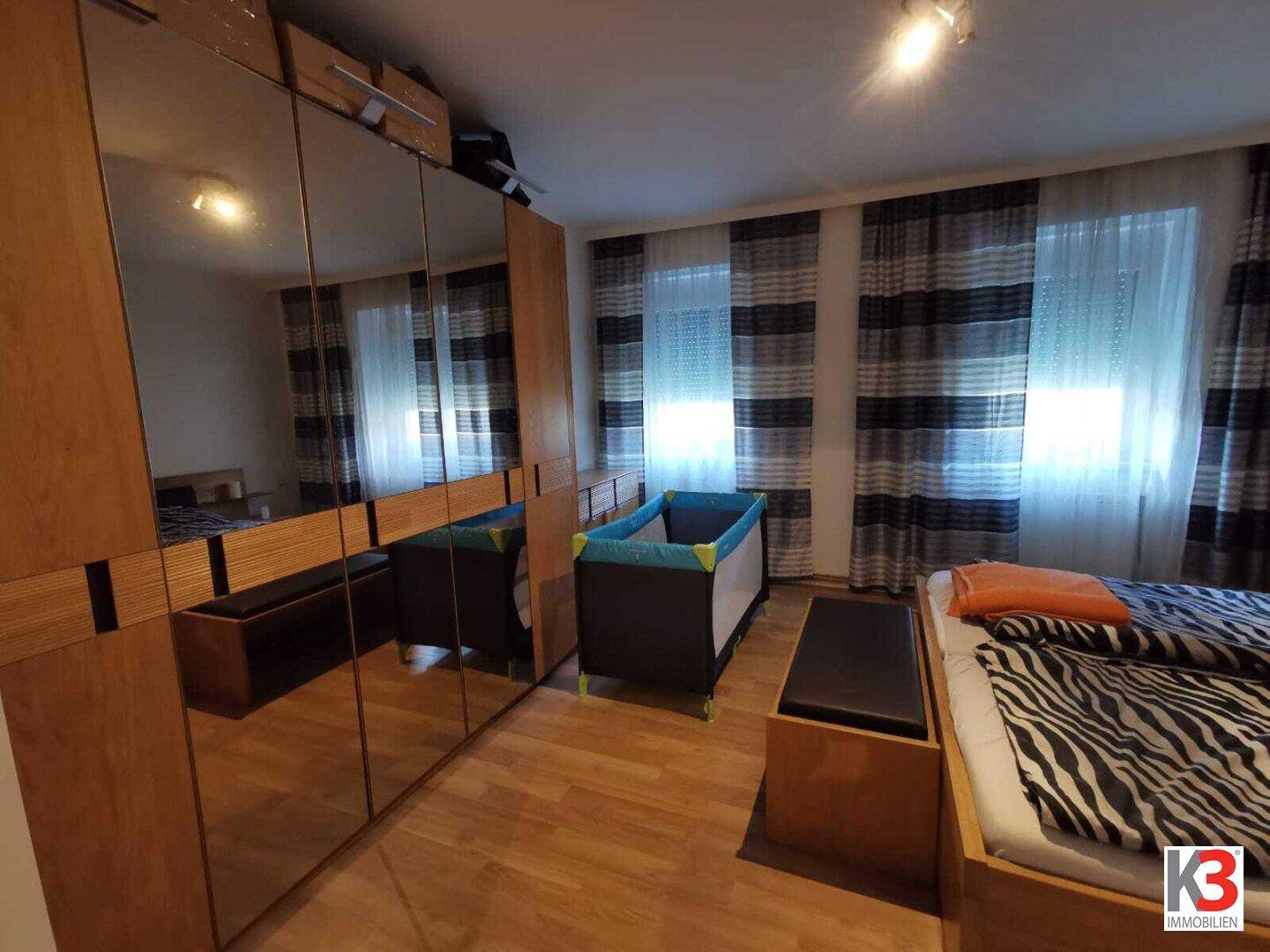 Das Schlafzimmer mit großem Spiegelschrank, Doppelbett und Babybett.