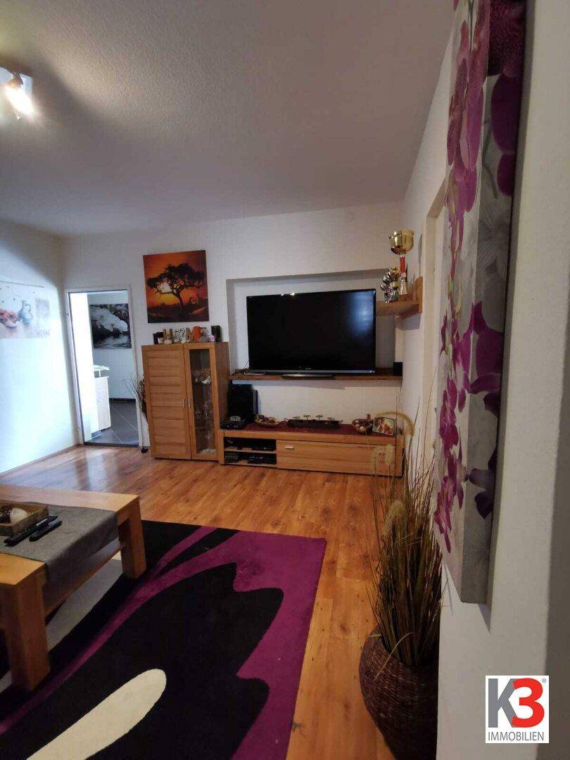Das Wohnzimmer mit Fernseher, Holzmöbeln und einem dekorativen Wandbild.