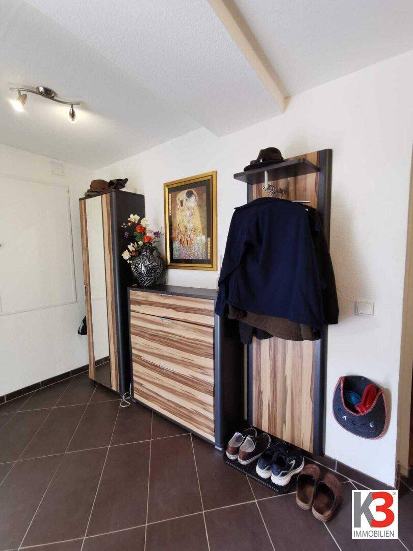 Der Flur mit dunklen Fliesen, Garderobe und Spiegel.