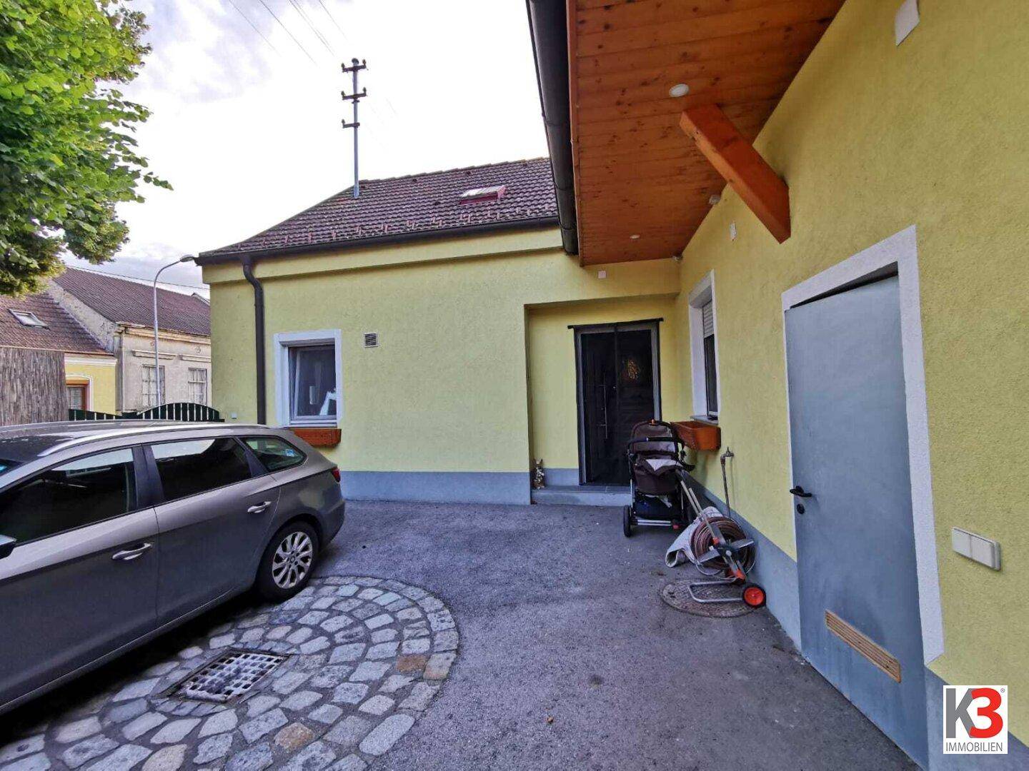 Der Eingangsbereich des Hauses mit gepflasterter Einfahrt und einem geparkten Auto.
