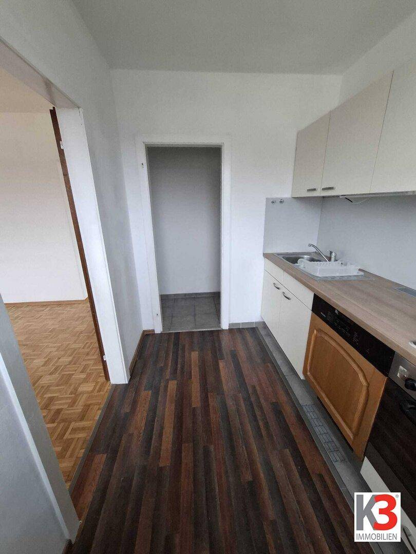 Funktionale Küche mit Einbaugeräten, Holzoptik-Arbeitsplatte und dunklem Laminatboden.