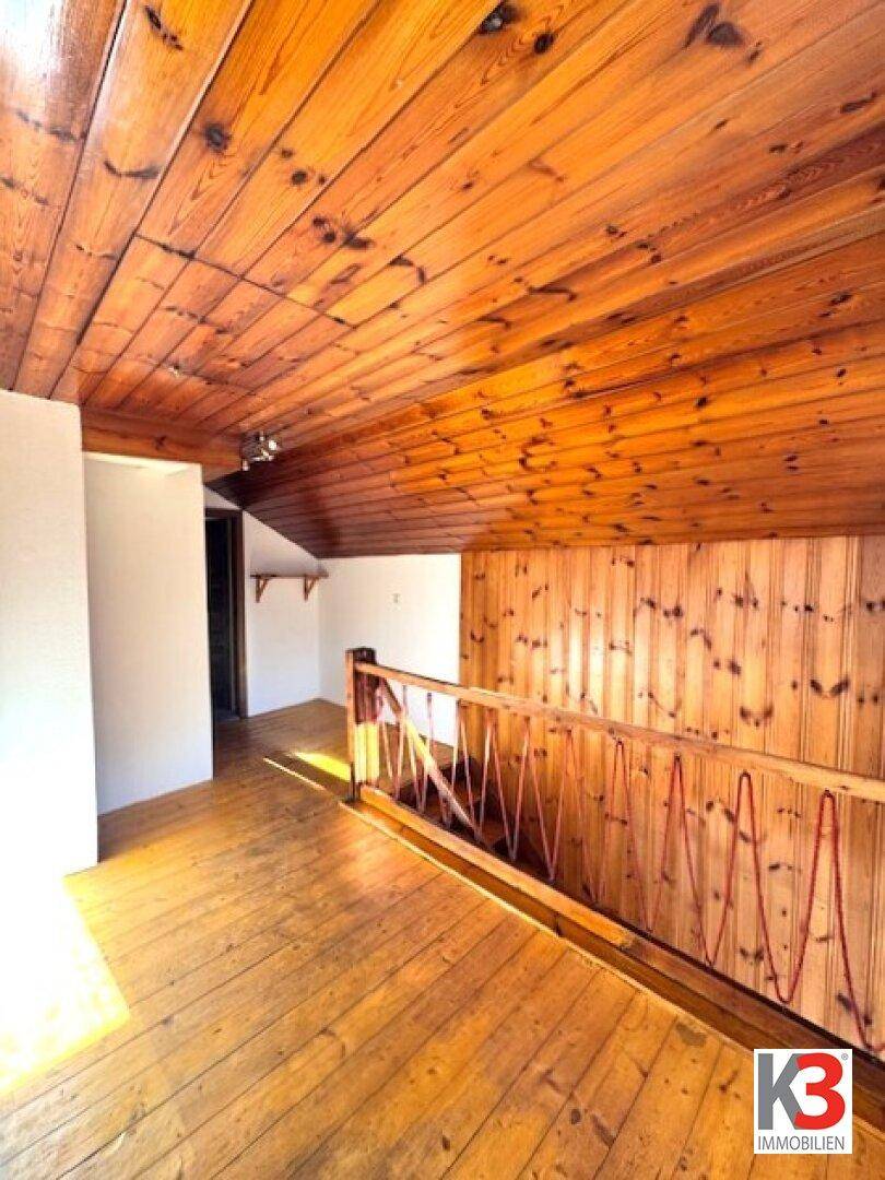 Rustikaler Flur mit viel Holz an Wänden, Decke und Boden, sowie einem Holzgeländer.