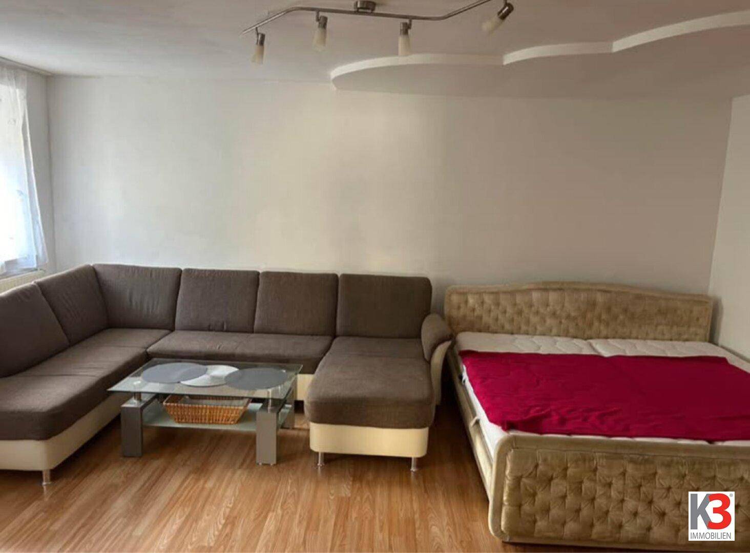 Wohnzimmer mit großer Eckcouch, Couchtisch und einem zusätzlichen Bett.