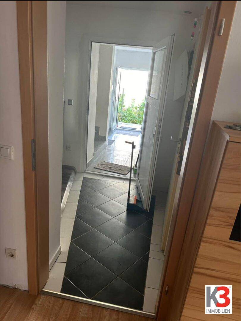 Heller Eingangsbereich mit Fliesenboden und offener Tür zum Außenbereich.