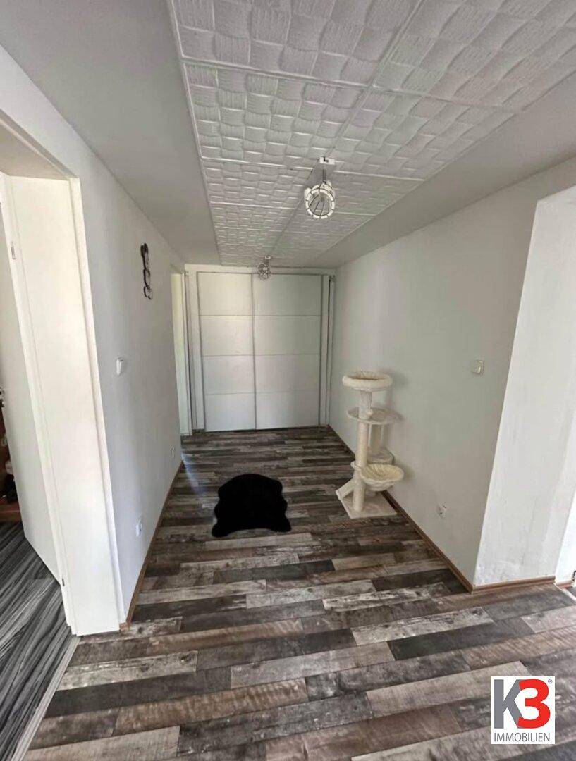 Langer Flur mit Laminatboden, strukturiertem Deckenpaneel und großem Einbauschrank.