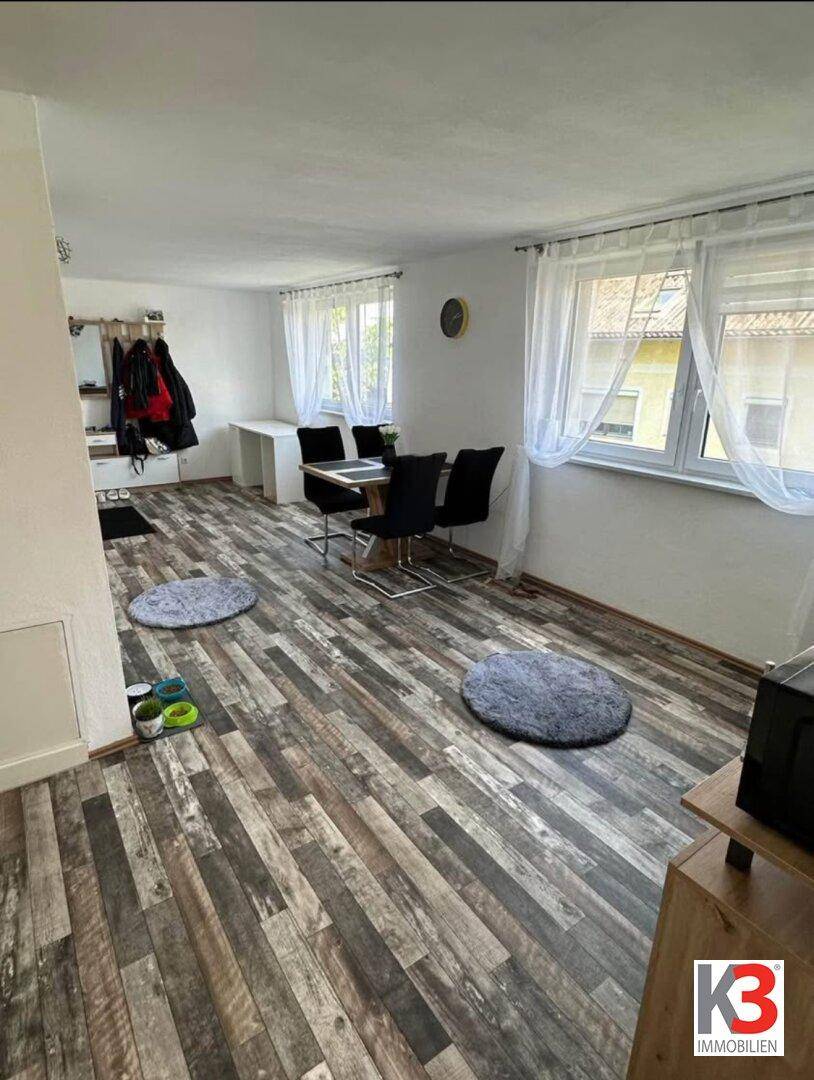 Offener Wohn- und Essbereich mit Laminatboden, Esstisch und Garderobe am Eingang.