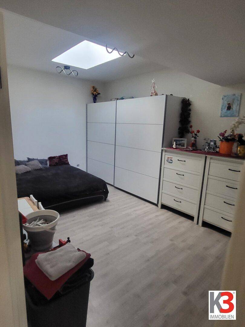 Schlafzimmer mit großem Kleiderschrank, Doppelbett und hellem Laminatboden.