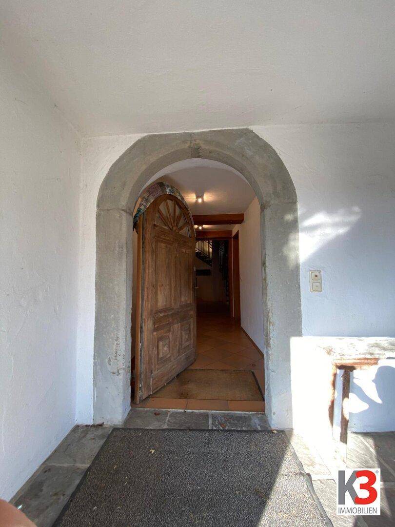 Historischer Eingangsbereich mit einem steinernen Rundbogen und einer massiven Holztür.