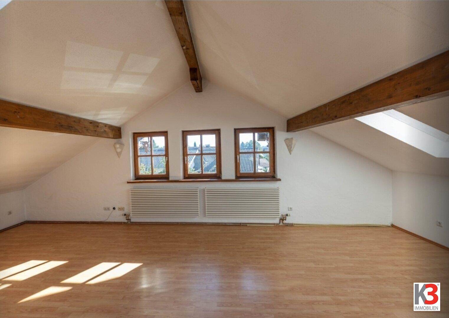 Geräumiger Dachbodenraum mit sichtbaren Holzbalken und schrägen Wänden, ideal zum Ausbau.