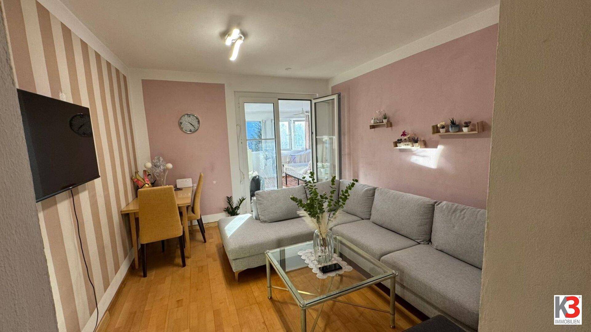 Gemütlicher Wohnbereich mit Sofa, Esstisch und Zugang zu einem hellen Außenbereich.