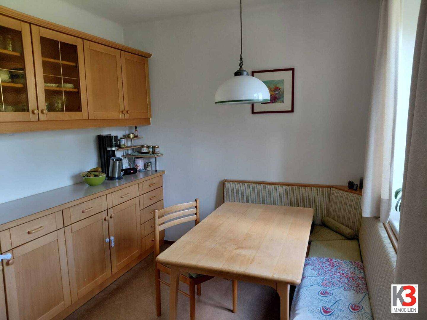 Gemütlicher Essbereich mit Holztisch, Eckbank und hellen Holzschränken in der Küche.