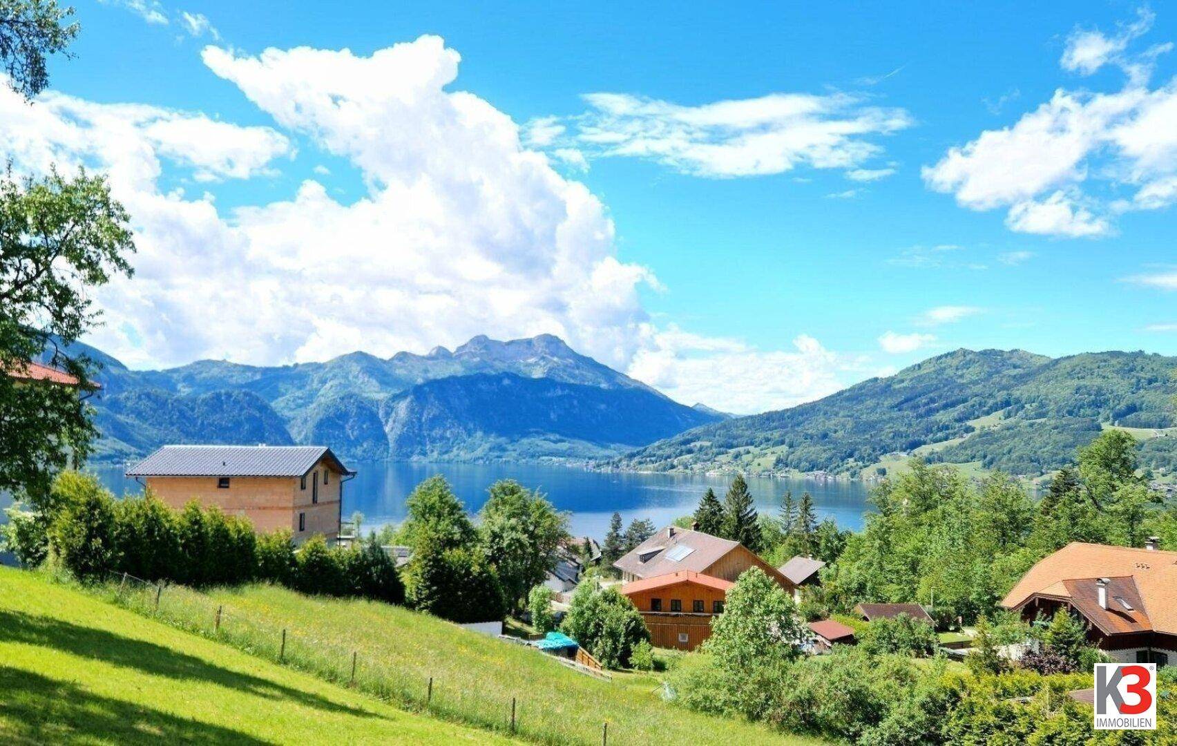 Panoramablick auf eine malerische Seenlandschaft mit Bergen und umliegenden Häusern.