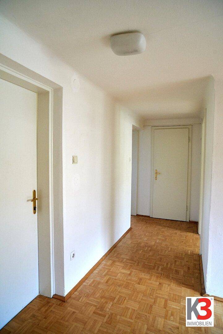 Heller Flur mit Parkettboden und mehreren weißen Türen, der verschiedene Räume der Wohnung verbindet.