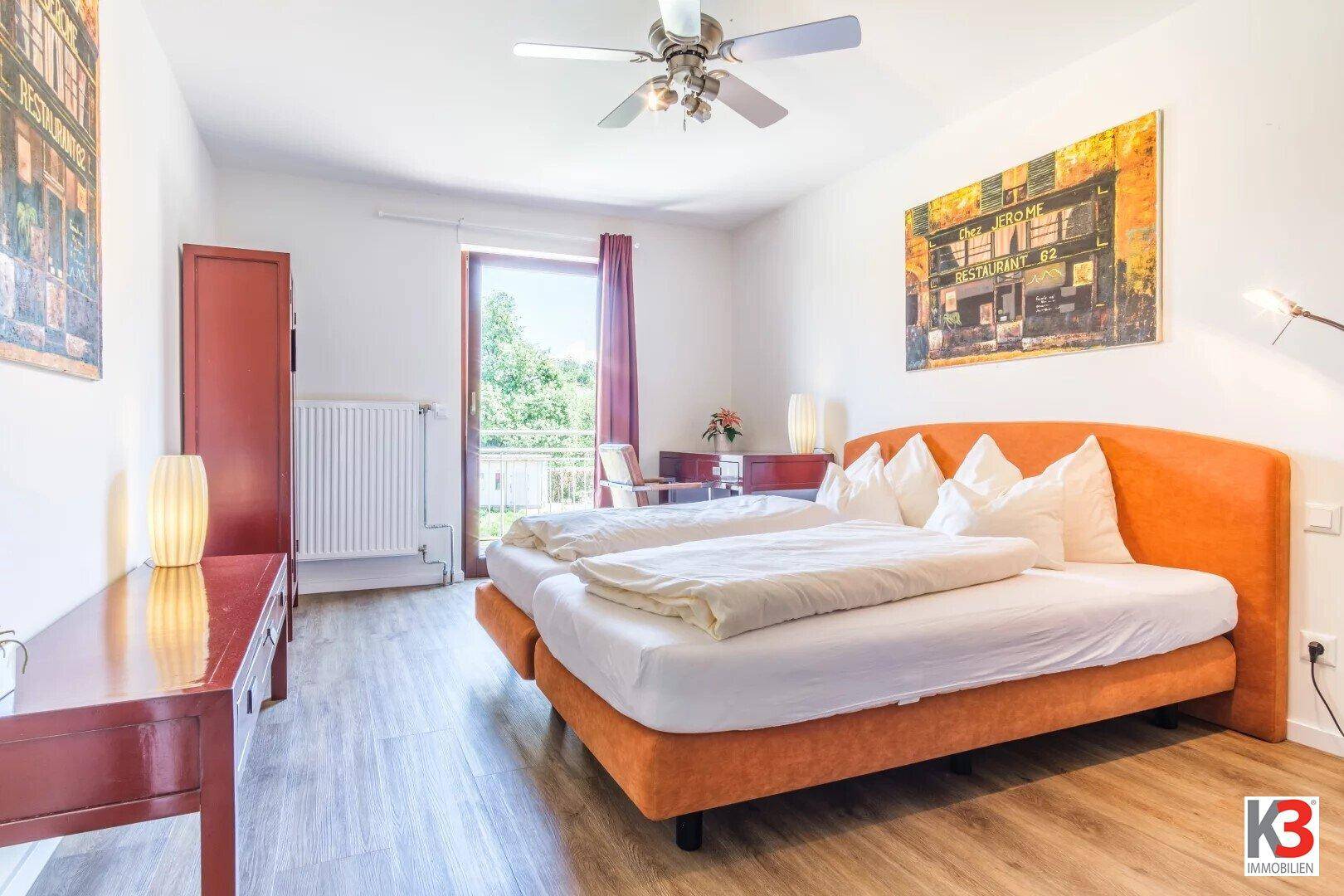 Helles Schlafzimmer mit Doppelbett, Deckenventilator und direktem Zugang zu einem Balkon.