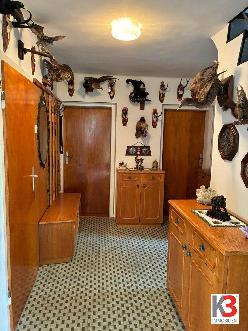 Geräumiger Flur mit traditionellen Holzmöbeln, Jagdtrophäen und kariertem Fliesenboden.