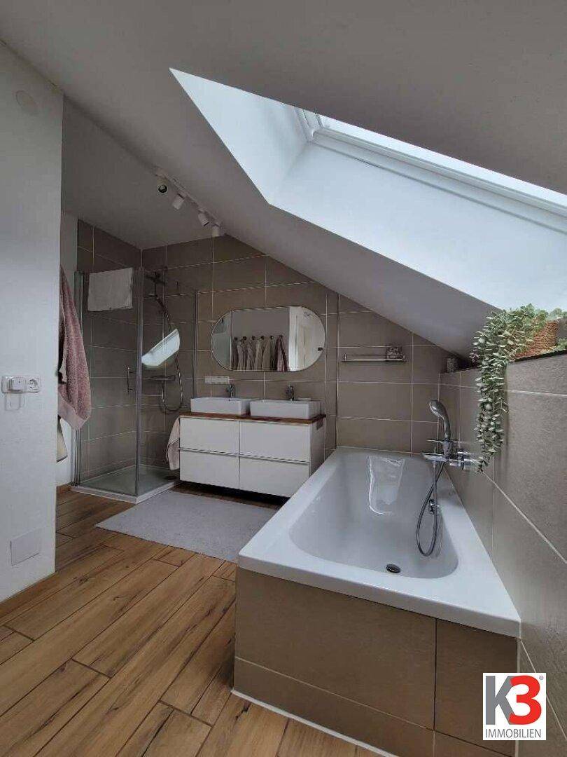 Modernes Badezimmer mit Dachschräge, Badewanne, Dusche und Doppelwaschbecken.