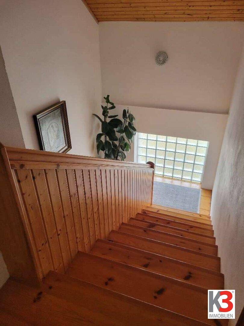 Helles Treppenhaus mit Holzstufen und Holzverkleidung, das die Etagen verbindet.