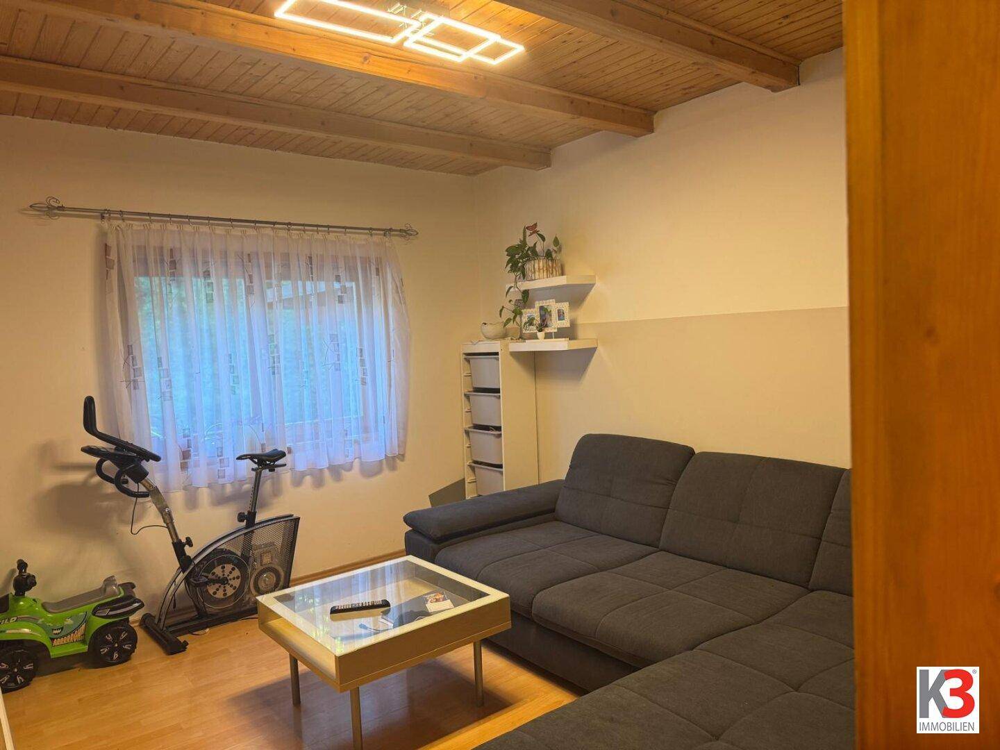 Vielseitiger Raum mit Sofa, Couchtisch und Fitnessgerät, ideal für Entspannung und Aktivität.