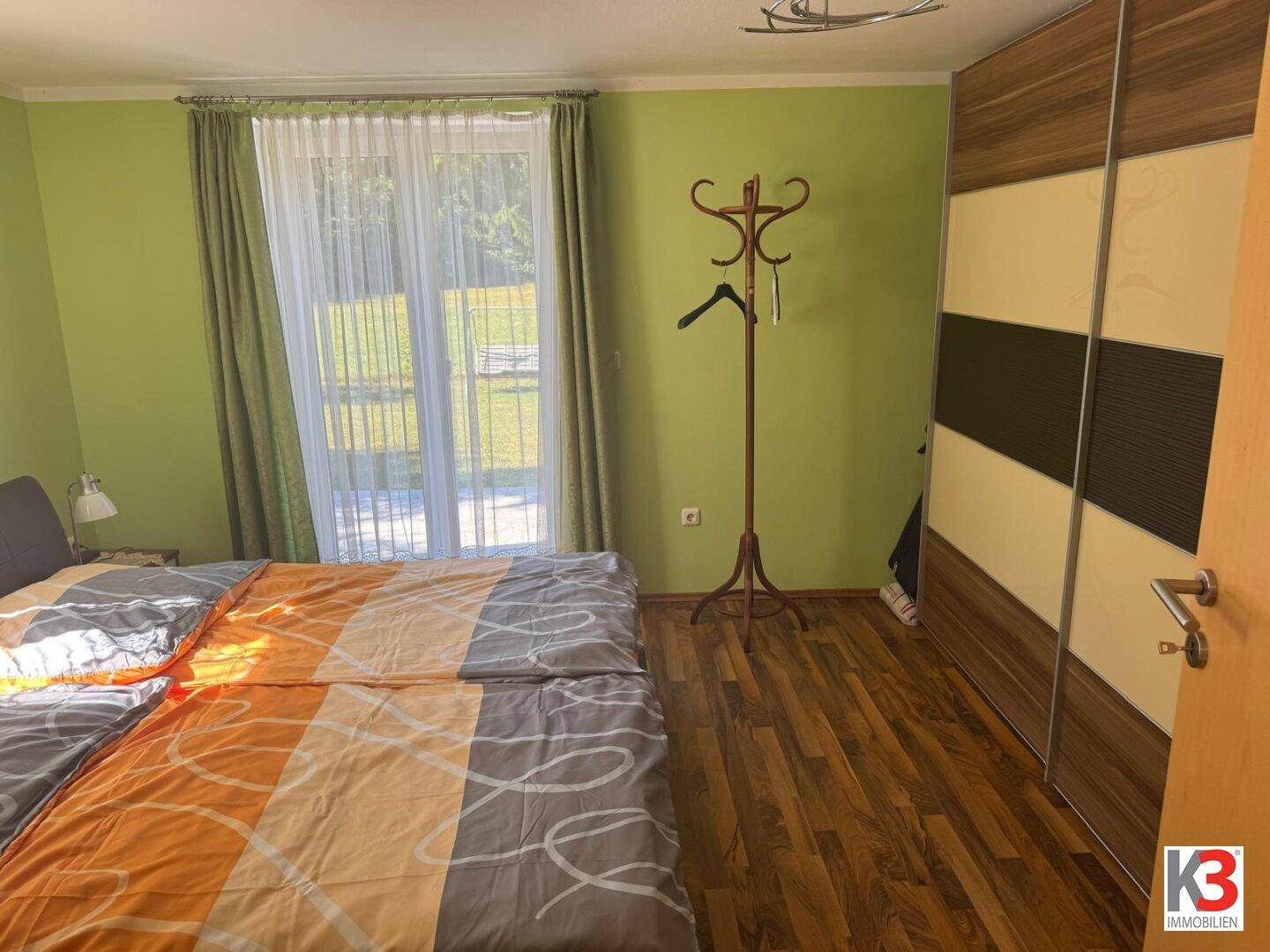 Schlafzimmer mit grünen Wänden, Doppelbett und großem Schiebetürenschrank.