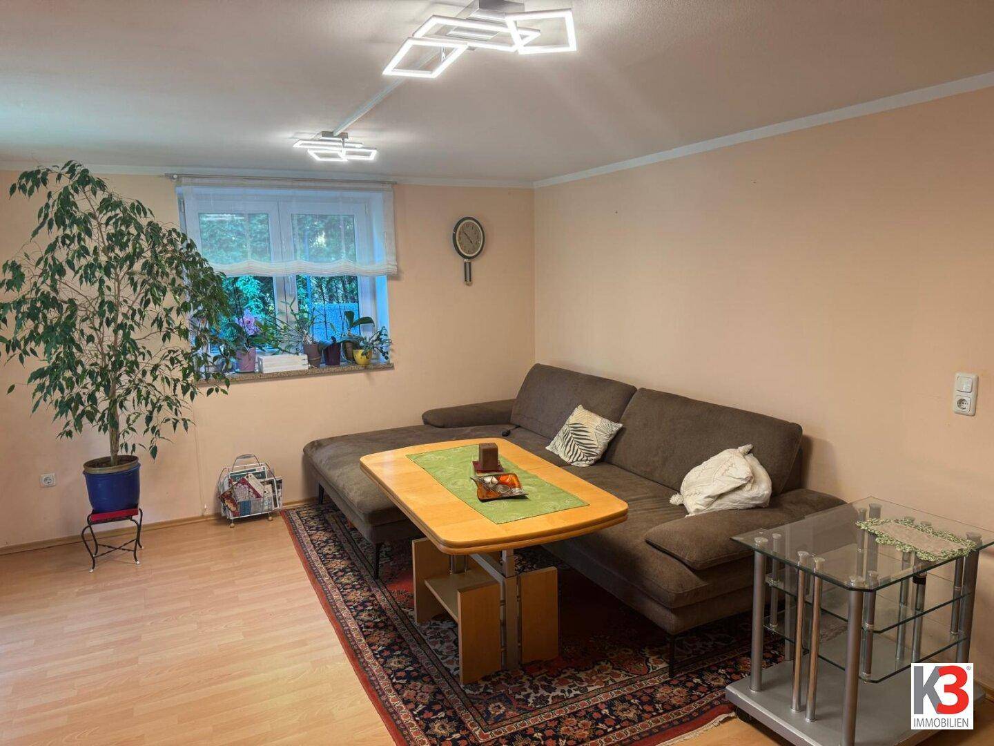 Geräumiges Wohnzimmer mit großem Ecksofa, Couchtisch und heller Laminatboden.