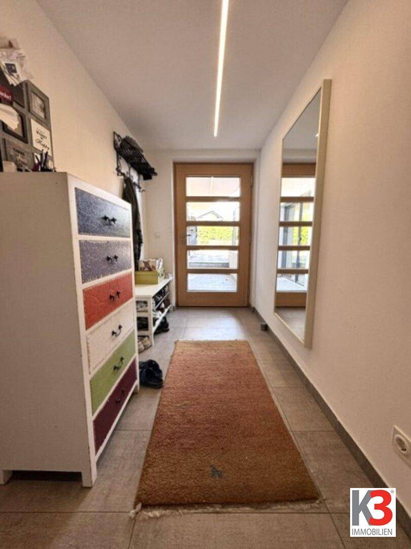 Heller Flur mit Fliesenboden, Garderobe und großem Spiegel.