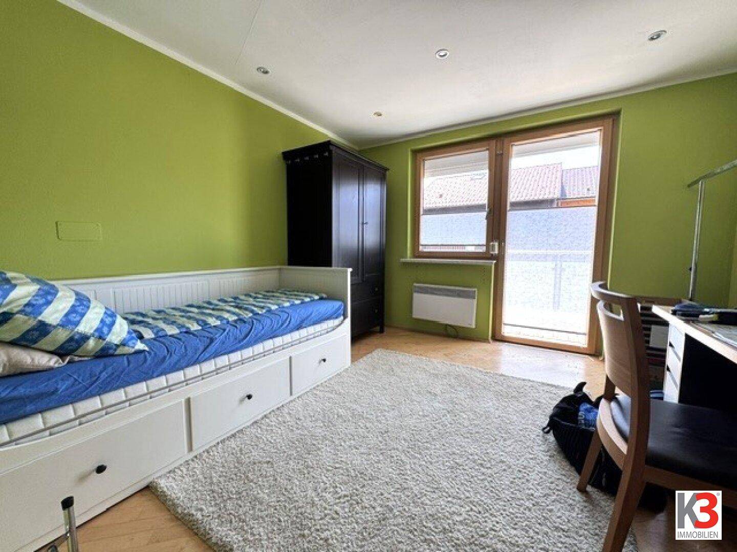 Kinderzimmer mit grün gestrichenen Wänden, Einzelbett und Zugang zum Außenbereich.